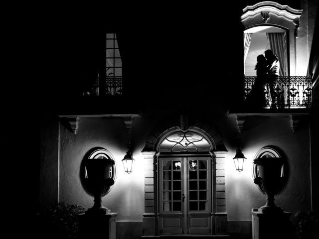 A newlywed couple in a window at night time - Wedding photography. 