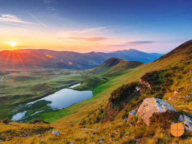 Stunning sunrise scenery in the alpine mountains. Mountain lake in the distance. Landscape Photography.