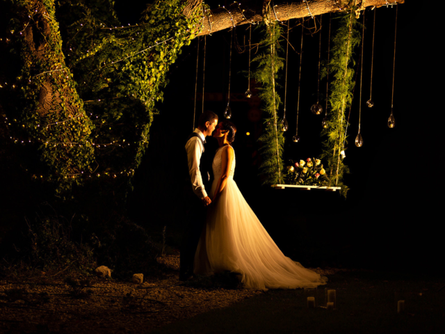 A newlywed couple dancing under a tree at night with lights around - Wedding photography. 