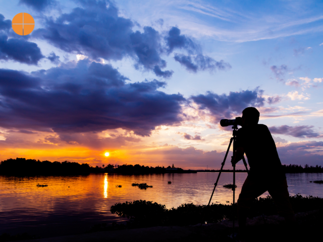 silhouette of photographer taking photo at sunset beside the river.